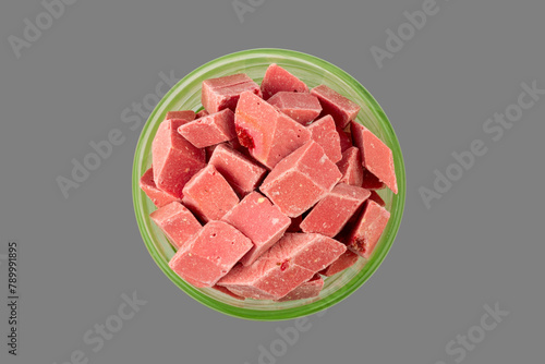 pink pieces of Uzbek dairy strawberry halva in a green bowl isolated on a gray background top view