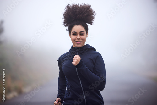 Girl, running and smile in morning fog in nature for health, fitness or wellness on road in portrait. Woman, person and athlete in workout, training and outdoor for speed, cardio and winter in Canada