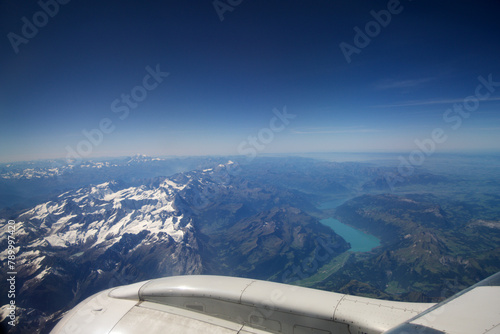 TURIN, ITALY - 13 SEP 2019: Aerial view above the clouds from a plane flying over the Swiss Alps, with mountain peaks covered in snow and a river flowing through the mountains