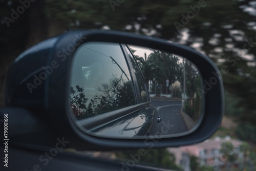 Car side mirror reflecting road during travel