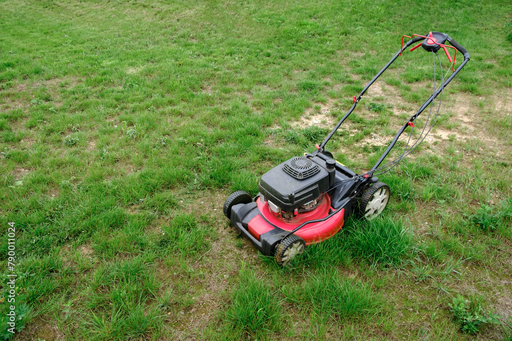 Lawn mover on green grass background. Machine for cutting lawns. Garden care. Electric equipment. Side view. Copy space. Lots of clover weeds. Sport lawn field for games. Banner. High quality photo Lawn mover on green grass background. Machine for cutting lawns. Garden care. Electric equipment. Side view. Copy space. Lots of clover weeds. Sport lawn field for games. Banner. High quality photo