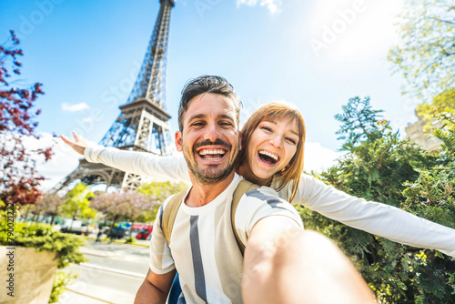 Happy couple of tourists taking selfie picture in front of Eiffel Tower in Paris, France - Travel and summer vacation life style concept