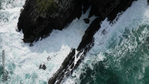 Aerial drone shot of foamy sea waves breaking on rocks photo