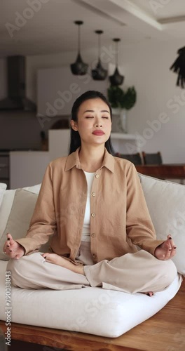 Female sit cross-legged on couch closed her eyes and do meditation practice, enjoy routine, relaxing mind and body, boost sense of inner calmness and harmony, improves concentration and mental clarity