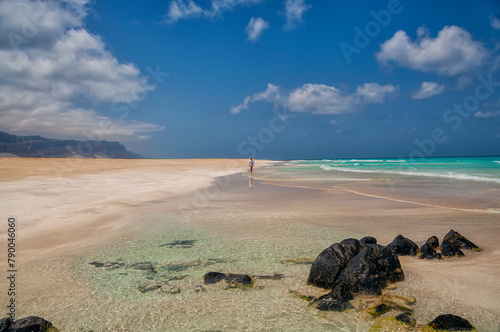 coast of an island in the Indian Ocean. Emerald water, pristine beaches, wild rocky shores. A girl in the distance walks along the beach. Amazing landscape. Yemen. Socotra.