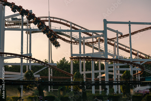 An anonymous player rides a roller coaster with the evening light as the background