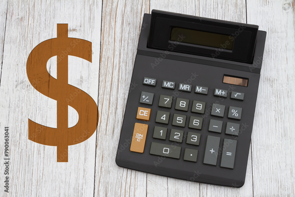 Obraz premium A black calculator with a gold dollar sign on wood desk