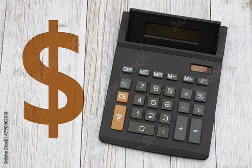  A black calculator with a gold dollar sign on wood desk © Karen Roach