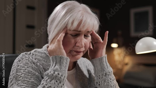 Headache, hypertension concept. Senior woman with headache and migraine suffers from eye pain and prolonged stress. Close-up of elderly gray-haired woman with overwork photo