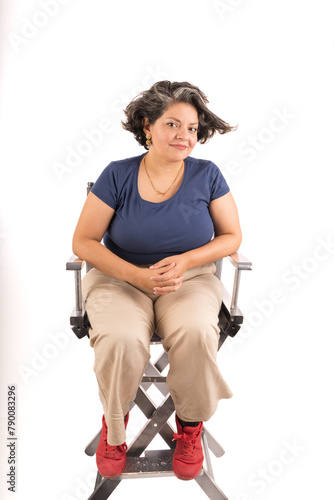 A woman sits in a chair with her hands on her lap