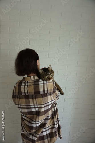 Woman holds a cat in her arms. Vertical photo.