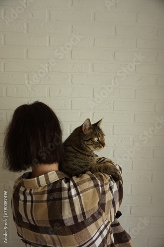 Woman holds a cat in her arms. Vertical photo.