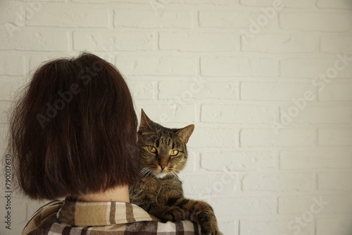 Woman holds a cat with yellow beautiful eyes in her arms.