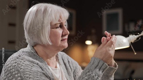 Pain in fingers. Sennior woman with gray hair is suffering from pain in her fingers and attacks of gout. Close-up of tired elderly woman with rheumatism and arthritis or arthrosis of joints photo