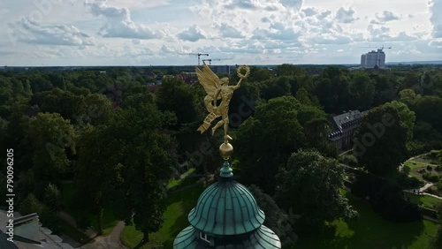 An aerial drone shot captures a golden statue atop the University of Münster , Westfälische Wilhelms-Universität-Münster in Germany .  photo
