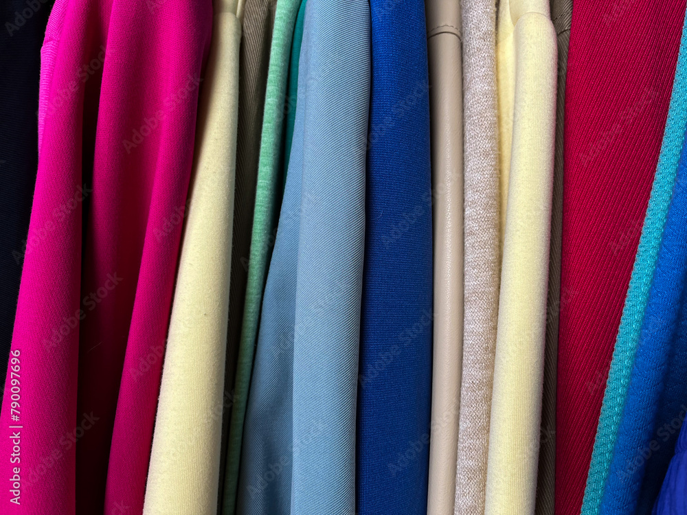 A closeup of a row of colorful jackets. Side view of clothes on a hanger in a store.