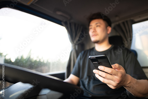 スマートフォンを操作しながら運転するトラックドライバー