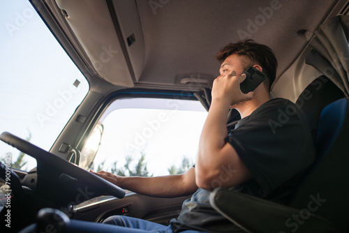 スマートフォンを操作しながら運転するトラックドライバー