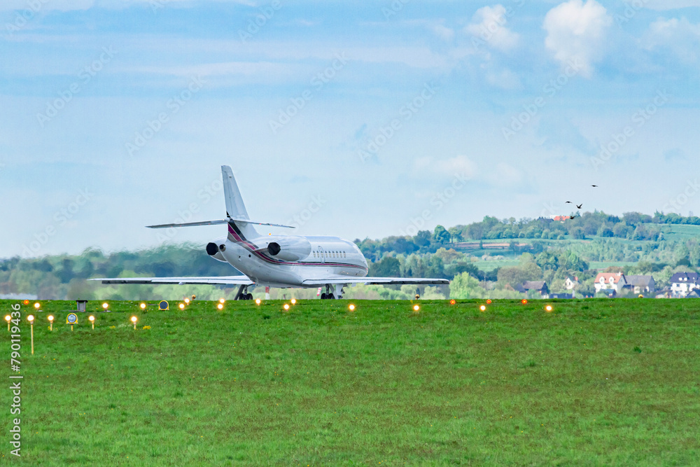Obraz premium Prywatny odrzutowiec kołujący na pasie startowym na malowniczym lotnisku w Balicach | A private jet taxiing on the runway at the picturesque airport in Balice