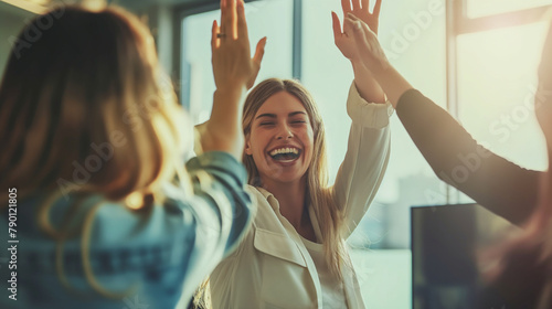 Surrounded by colleagues offering congratulations, a white woman shares a high-five in her office, her expression one of elation and excitement, her beaming smile radiating happine photo