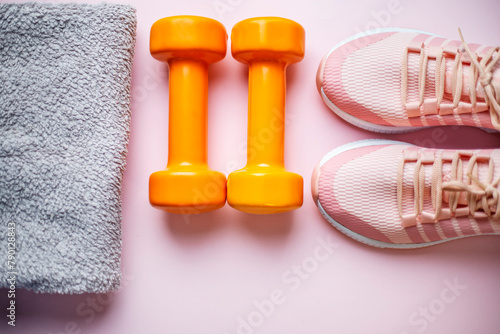 Fitness concept with pink sneakers, dumbbells and towel on pink background top view © Yelena