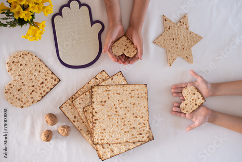 Children hands hold Matzah shape of heart. Traditional of Jewish Holiday on Passover. Home symbol of lovely family. top view, layout. love and care. Gift for lovers. big happy family in love