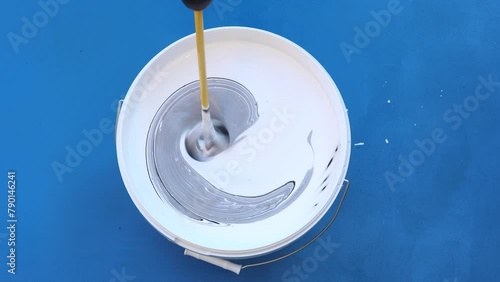 Paint mixer is placed in wall paint bucket to mix and stir three paint colors.