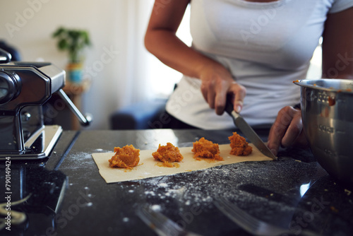 Person  hands and cooking pasta on kitchen counter with knife at home for healthy diet. Woman  chef and food with mixing bowl in closeup for handmade ravioli and preparation of balanced meal