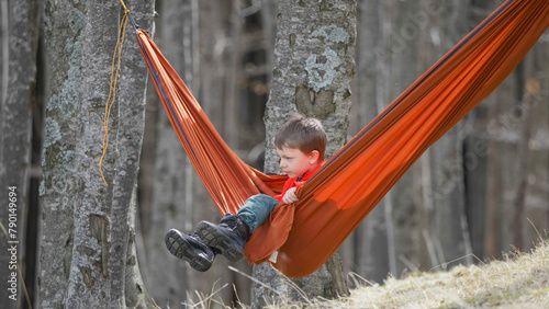 Little kid swinging in hammock between the trees of the forest