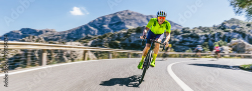 Mature Adult on a racing bike climbing the hill at mediterranean sea landscape coastal mountain road - mallorca mountains. high speed motion blur effect