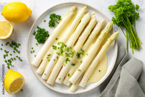 tasty white asparagus with creamy sauce hollandaise on a plate, top view, delicious vegetarian dish