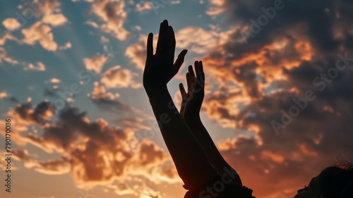 Silhouette of hands reaching upwards towards a dramatic sunset sky with clouds. Hope and aspiration concept. Design for motivational poster, spiritual event flyer, and self-growth workshop banner.