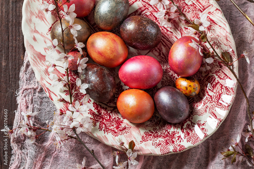 Eggs painted in different colors and covered with mother-of-pearl, and blossoming plum branches. Easter concept.