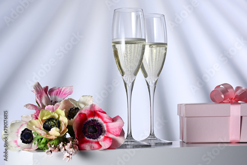 Two glasses with champagne, gift and flowers