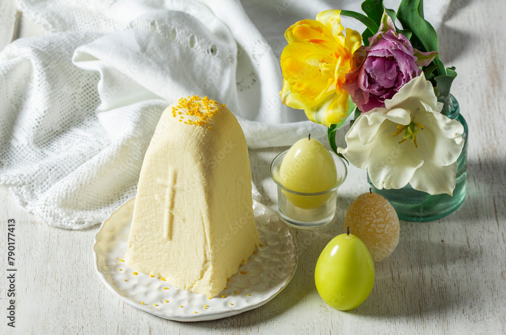 Traditional Slavic Easter dish made from cottage cheese - Paskha, a bouquet of tulips and candles on a light background.