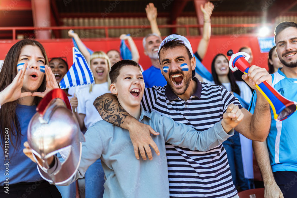 Greece fans cheering at the game on stadium. Wearing blue and white colors to support their team. Celebrating with flags and scarfs. Greece fans cheering at the game on stadium. Wearing blue and white colors to support their team. Celebrating with flags and scarfs.