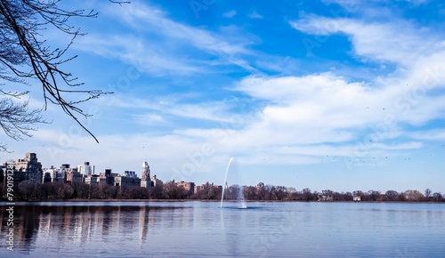 Jacqueline Kennedy Onassis Reservoir, Central Park, New York City, New York. Lake on a beautiful early spring day with blue sky and wispy clouds, fountain in the center. Popular jogging spot. photo