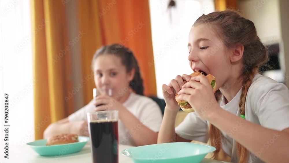 children group eating fast food in the kitchen. delicious breakfast unhealthy food concept. children girls eat hamburgers and lifestyle drink cola in the kitchen indoors. fast food concept