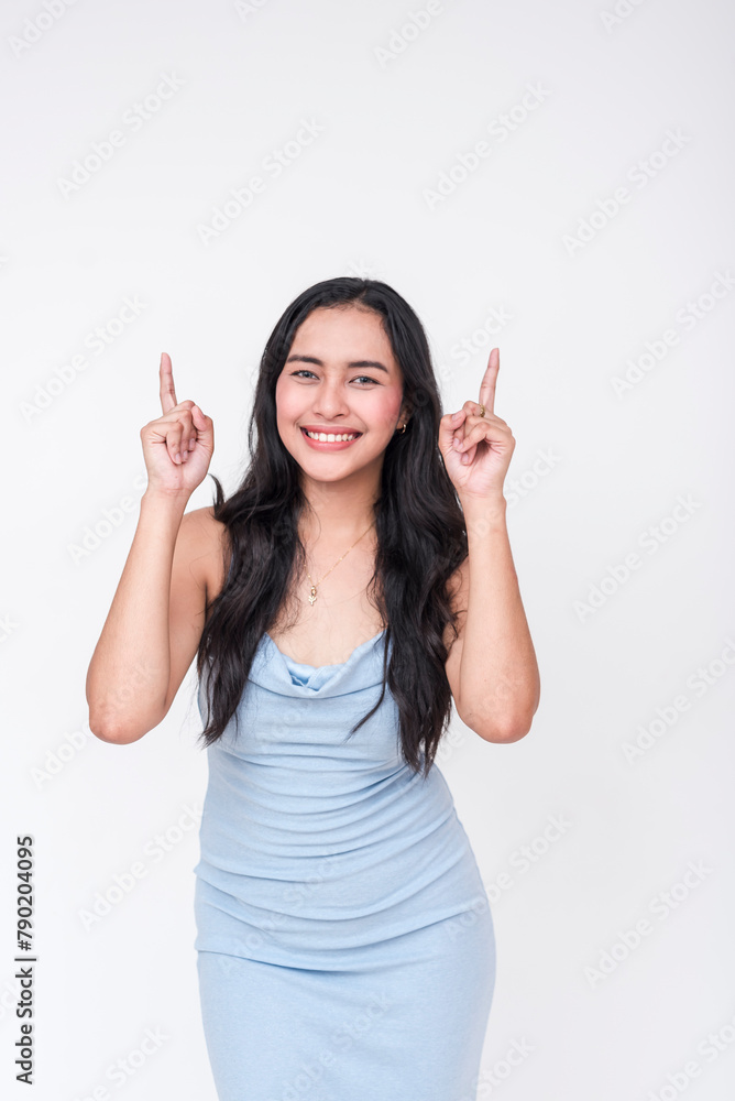 Cheerful young woman in a baby blue dress pointing upwards, isolated on a white background Cheerful young woman in a baby blue dress pointing upwards, isolated on a white background