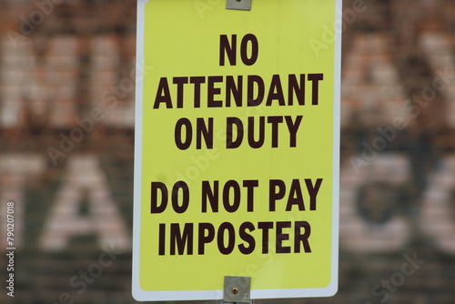 An addition to a current posted sign in a parking lot. The digital  self serve machines have had a fake attendant standing in front of the machine.