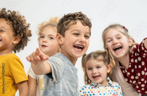 happy children of different races in bright T-shirts hug each other and smile at the camera, with a white modern classroom in the background.