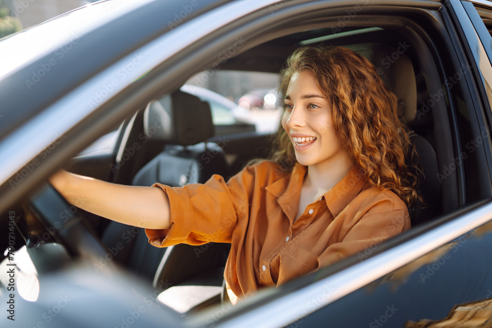 Naklejka premium Young woman driving a car. Leisure, travel, weekend, navigation.