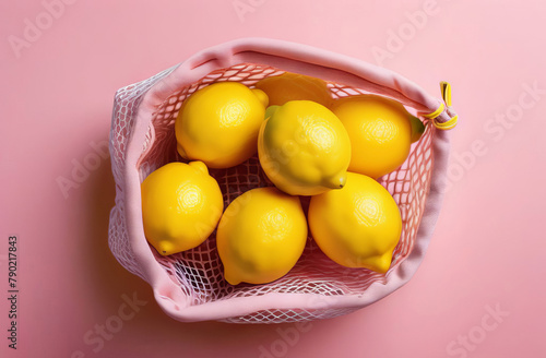 From above pink string cotton sack with fresh healthy lemons placed on pink background photo