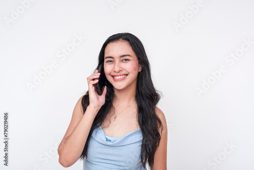 Smiling young woman in a baby blue dress talking on a cellphone