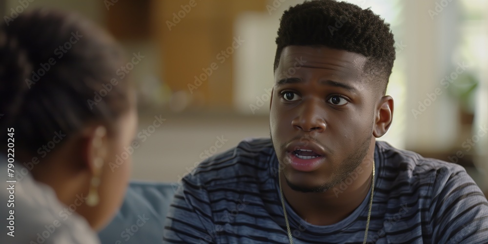 Young Black Man Engaged in Conversation with Therapist, Brown Eyes and Beard, Serious Expression, Indoor Setting Young Black Man Engaged in Conversation with Therapist, Brown Eyes and Beard, Serious Expression, Indoor Setting