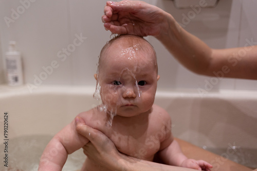 beautiful mixed race baby bathing in the bathtub. close-up shot, water pouring on the face