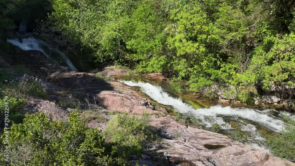 A large mountain waterfall against a background of green forest flows down a natural stone chute