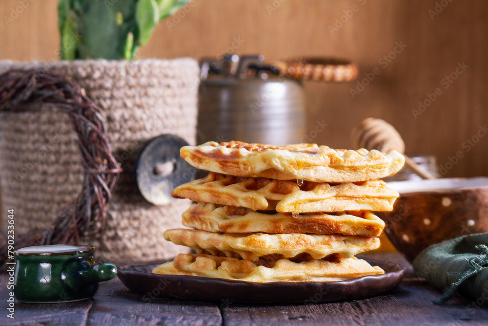Belgian waffles served with honey, cream and sai on a wooden background. Rustic style.
