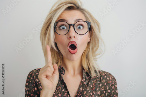 I have an idea. Young energetic woman raises her index finger up as a sign that a bright idea or thought has occurred to her. On a gray background. photo