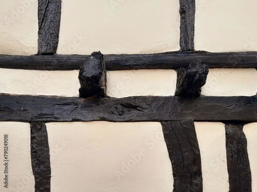 White cement rough wall background with black wooden slats. Detail of beams, lumber and other construction materials. Architecture and Construction.